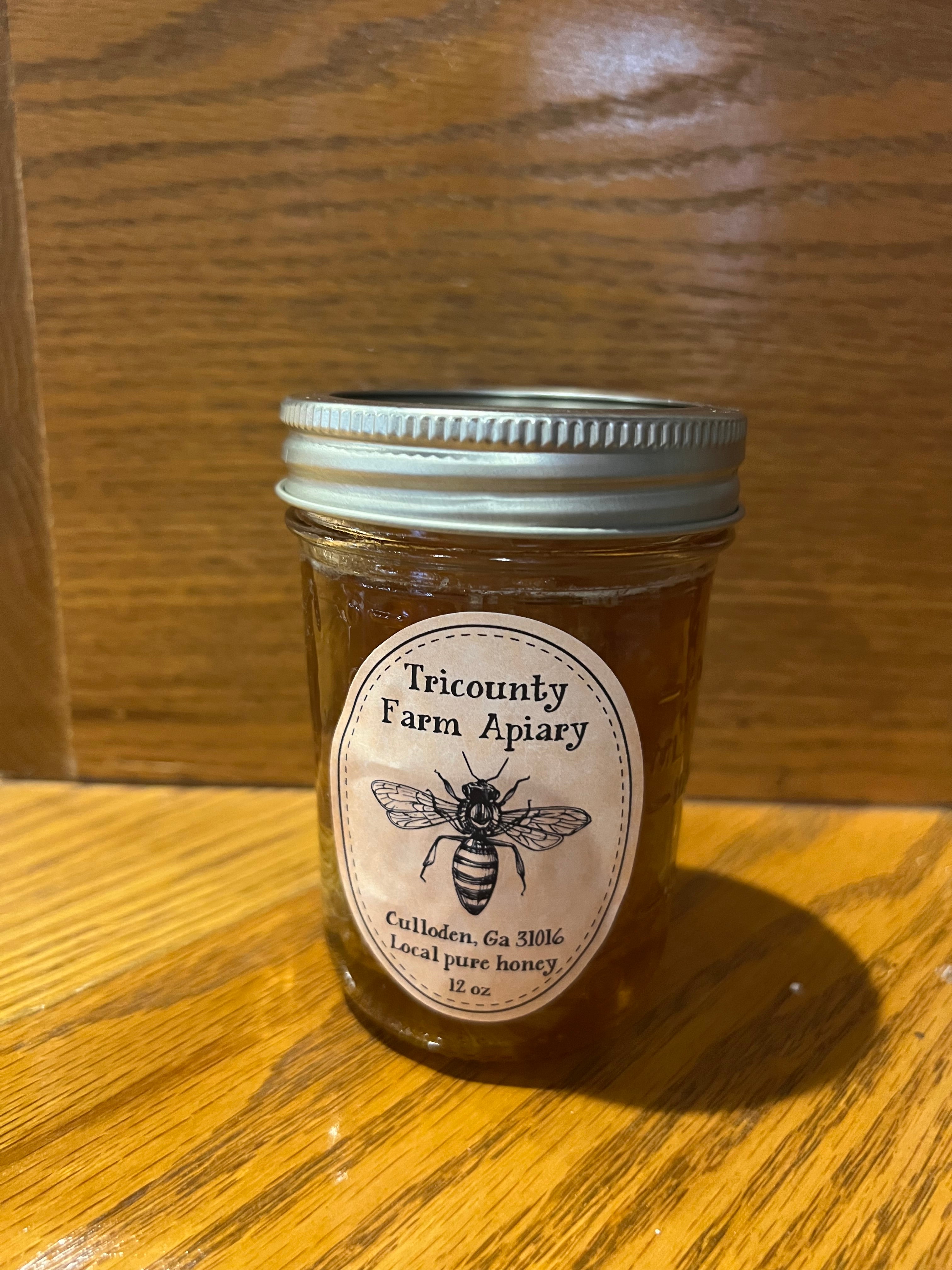 12 oz jar of Tricounty Farm honey, golden amber color, with a classic label and a metal lid.